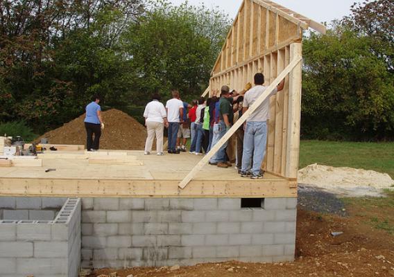 Volunteers secure the north end wall of the house after it is lifted into place. 