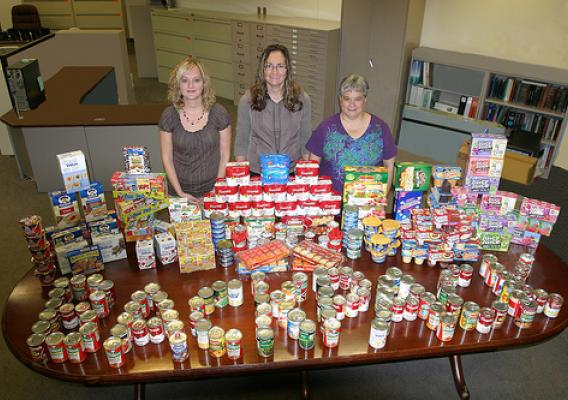 Feds Feed Families:  (left to right), Traci Ross, Farm Service Agency Coordinator; Tammi Schone, Rural Development Coordinator; and Linda Weinzetl, Natural Resources Conservation Service Coordinator with some of the food collected for the backpack program. 