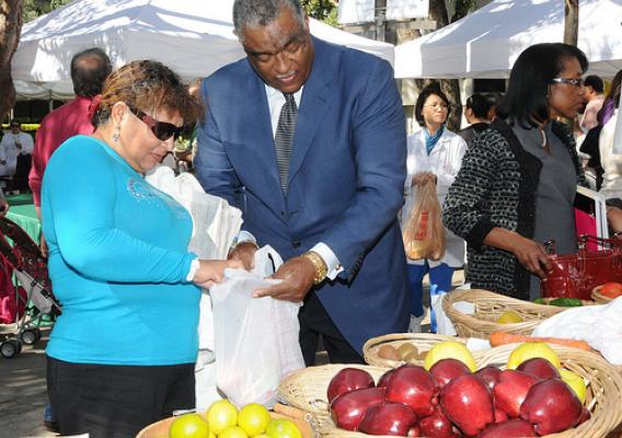 SERO Regional Administrator Don Arnette assists SNAP client Maria Salgado with bagging the fresh fruits and vegetables she purchased at the Jackson Memorial Foundation Green Market, Miami, Fla., with her SNAP benefits.   
