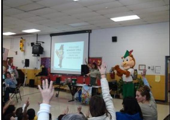 Kindergarten through second grade students at Braddock Elementary School raise their hands to answer questions about recycling from Woodsy Owl and Forest Service staff as a part of a recycling program initiated by the school.