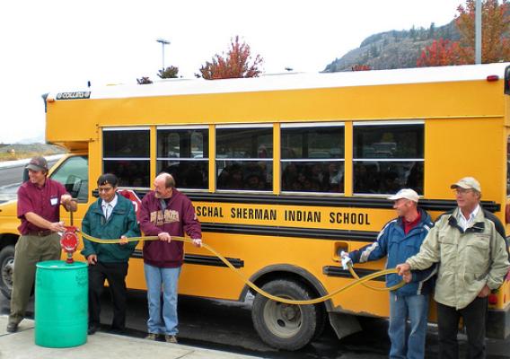 A biodiesel blend containing oil from winter canola is pumped into a Paschal Sherman Indian School bus. Pictured left to right: Washington State University extension specialist Phil Linden, Colville Confederated Tribes member Ernie Clark, ARS agronomist Frank Young, ARS technician Larry McGrew, and local grower Ed Townsend. Photo by Carla Des Voigne.
