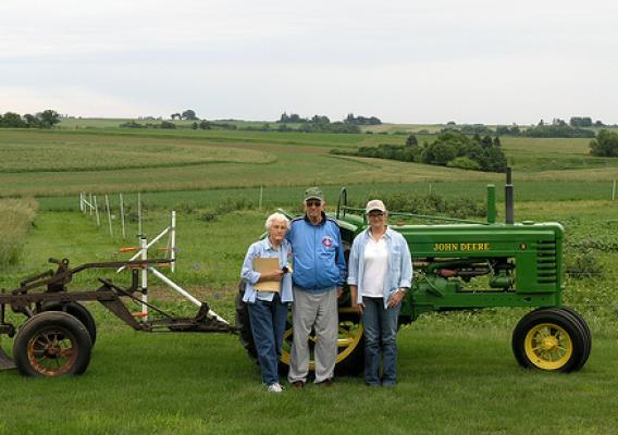 Caryl Radatz with her parents, Charles and Coralyn Radatz, in front of John Deere tractor used to install contour strips in 1943.
