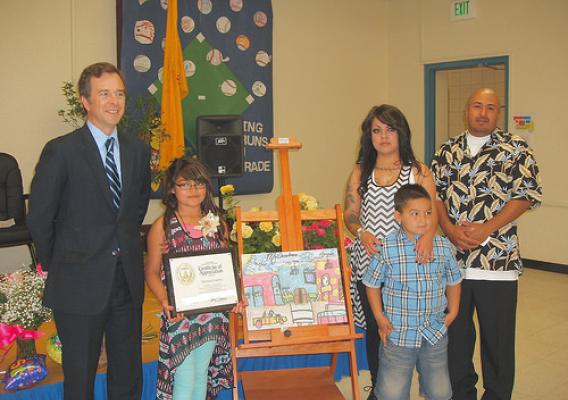 State Director Terry Brunner presents an award to Mireya Cisneros as her parents and her younger brother look on.
