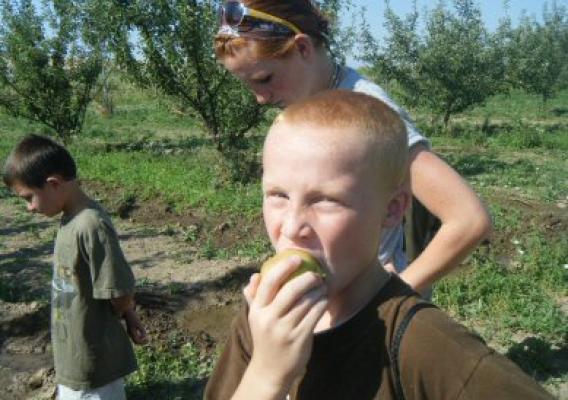 A participant enjoys an apple fresh from the tree during a Boys and Girls Club field trip to a local farm.