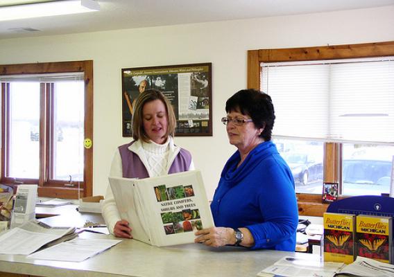 District Conservationist Jennifer Taylor (left) and Earth Team volunteer Susan Anderson look at book Anderson put together to show producers local plants that can be used to protect soil and provide wildlife habitat.