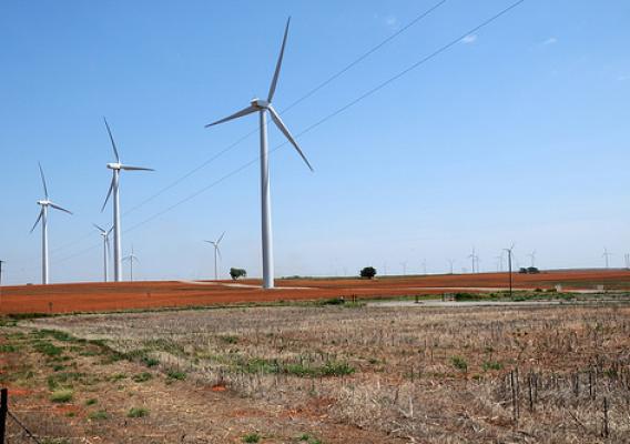 A tractor tills the soil among wind turbines in Oklahoma on August 13, 2009. USDA photo by Alice Welch.