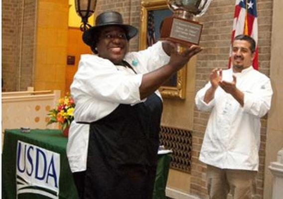 Caption 1: Chili champion, Shirley Brown accepting the silver chili bowl trophy at the 2011 Hispanic Heritage Food Fiesta. In the background is Chef Pedro Matamoros applauds Shirley’s victory.
