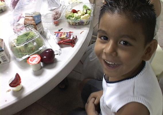 A young SNAP recipient eats at the Help 4 Kidz Café while his parents apply for SNAP with the help of a volunteer case manager.