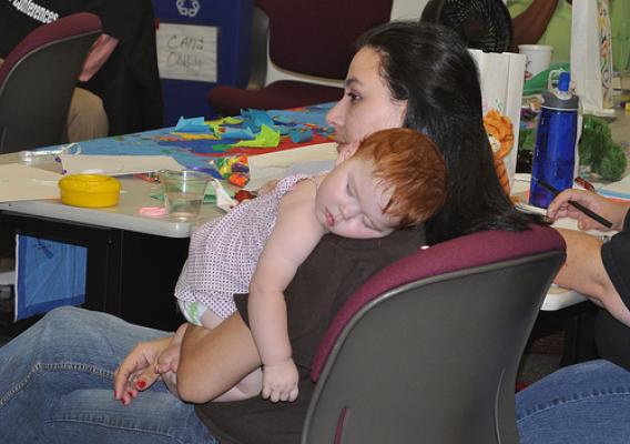 A local WIC staff member holds her sleeping baby as she listens to the peer counseling instructor.