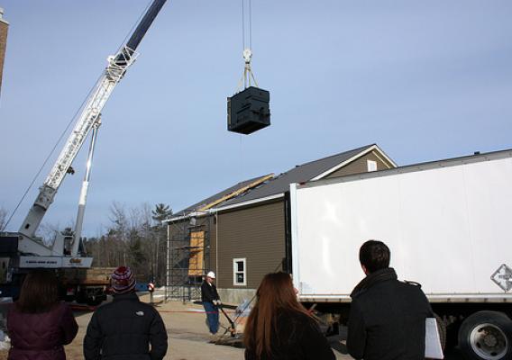 Maine Fuels for Schools. The firebox for Poland Regional High School's new Recovery Act-funded biomass heat system is hoisted into the boiler house, as school Principal Cari Medd (hat) and guests look on.
