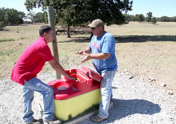 Mike Whitis, left, Benton County NRCS district conservationist, and Craig Oliphnant discuss the operation of Oliphnant’s new livestock watering tank. 