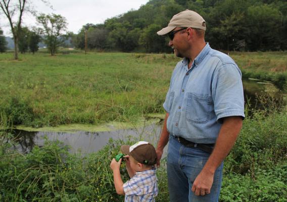 Ryan Pulley and his son look at Pine Creek, which flows through the land where he raises beef cattle in southeastern Minnesota. Photo: Julie MacSwain.