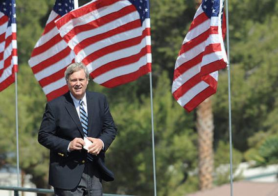 Agriculture Secretary Tom Vilsack behind a row of American flags
