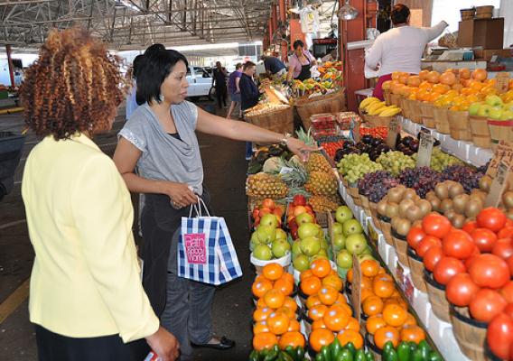 Food and Nutrition Service employees Jackie Garrett, right, and Angela Mathis, left, inquire about the price of grapes at a produce stand at the Dallas Farmers Market. 