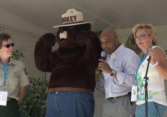 (From Left to Right) National Get Outdoors Day Colorado Coordinator Susan Alden-Weingardt, Smokey Bear, Mayor Michael Hancock, and Emcee, Coach Stacy Fowler celebrate National Get Outdoors Day Colorado 2012 on the main stage of the event.