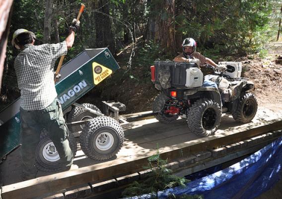 Mike Wubbels, a member of The Stewards of the Sierra National Forest volunteer group, works with a forest trailshot crewmember on a bridge replacement for an off-highway vehicle trail.  Their work involved installing water bars to prevent sedimentation and protect water quality.  