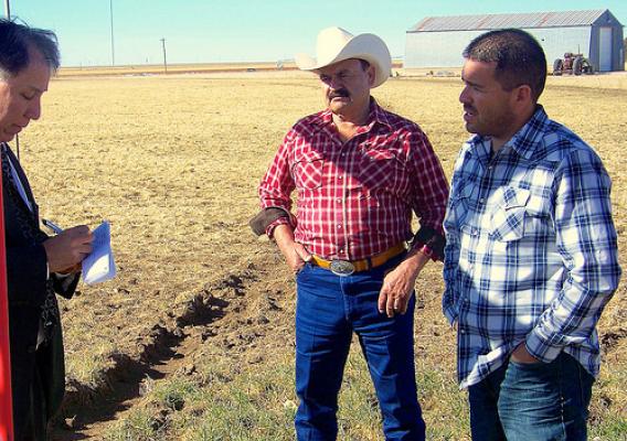 Under Secretary Ed Avalos (left) listens to Carlos and Greg Chavez explain the ongoing effects of drought on farms in Texas. Greg, a next generation farmer, has worked to increase the sustainability and success of his family farm by implementing new technology and irrigation methods that decrease water consumption.