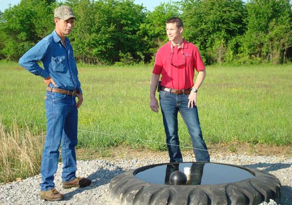 Dale Courtney (left) visits with Randolph County NRCS District Conservationist Adam Eades near an electric fence and tire tank watering facility about the resilience a good prescribed grazing program offers during a drought.