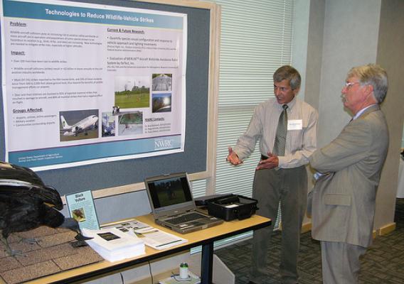 A researcher from USDA-APHIS’ National Wildlife Researcher Center discusses new technologies for reducing bird-aircraft collisions with a stakeholder at an event in 2010.