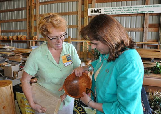 Susan Curington of North Woods Figured Woods (left) shows State Director Vicki Walker (right) how the family business “upcycles” burls, stumps and small, odd-shaped, or difficult-to-use wood pieces to be sold at premium prices to carvers and other hobbyists. USDA photo.