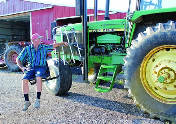 Mark Hosier, paralyzed from the waist down, uses a mechanical lift to board his tractor. Hosier works with the NIFA-funded AgrAbility Program to overcome disabilities and continue working as an agricultural producer.  Photo courtesy of National Swine Registry/Seedstock EDGE.