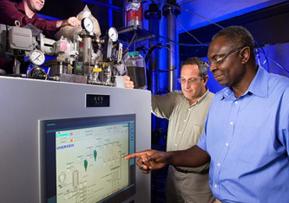 ARS chemical engineer Akwasi Boateng (right) and mechanical engineer Neil Goldberg (center) adjust pyrolysis process conditions while chemist Charles Mullen (left) loads the reactor with bioenergy feedstock. 