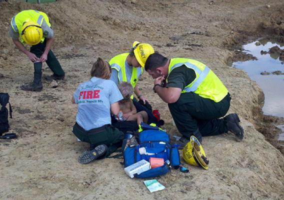 Rescue crews from the Ozark-St. Francis National Forest attend to three-year-old Landen Trammel whom they found Wednesday, Sept., 12 in Stone County, Ark. From left are Jamie Martin, Carol Swboni and Bradley Taylor who spotted the toddler playing in a mud puddle.  Photo credit: Courtesy of Fox16.com 