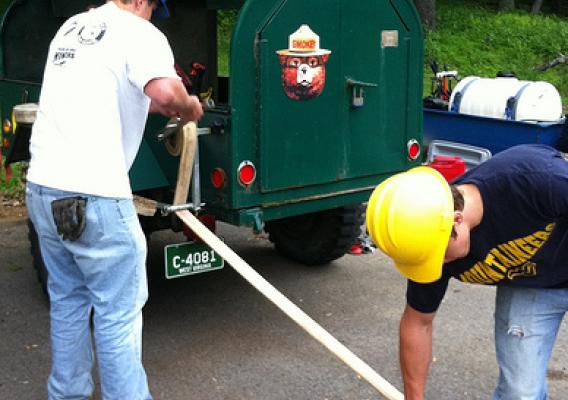 Wildland firefighter trainees windup a hire hose.  