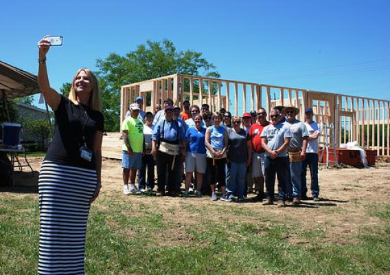 Homeowner Michelle Amrine taking a selfie with a crew of folks helping her build her home