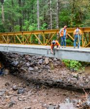 Workers insert a tie rod to help provide stabilization for the new bridge on Road 29 in the Umpqua National Forest's Tiller Ranger District